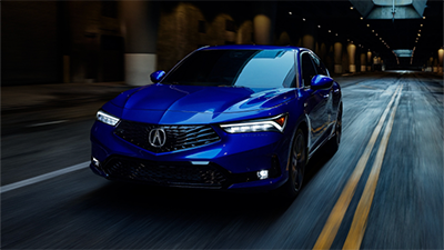 Front view of a blue Acura Integra at night with headlights on/Vue de face d’une Acura Integra bleue la nuit, avec phares allumés.