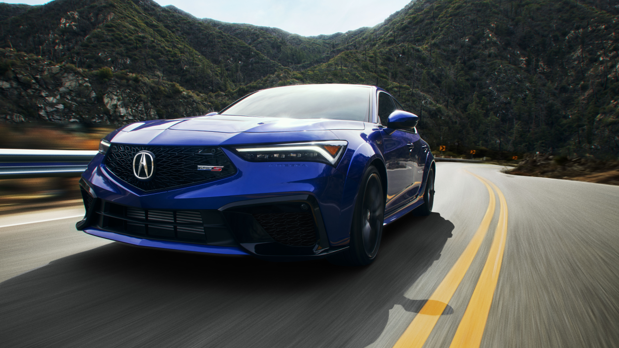 Plan de trois quarts avant d’une Integra Type S bleue roulant sur une autoroute de montagne.