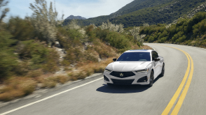 Plan avant d’une TLX blanche prenant un virage sur l’autoroute.