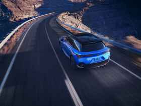Bird’s eye 3/4 rear view of blue ZDX driving on desert highway at dusk.