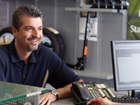 View of man sitting at a desk,  interacting with an Acura specialist.