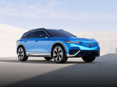 Vue 3/4 avant du ZDX bleu stationné, entouré d'une architecture moderne et minimaliste.