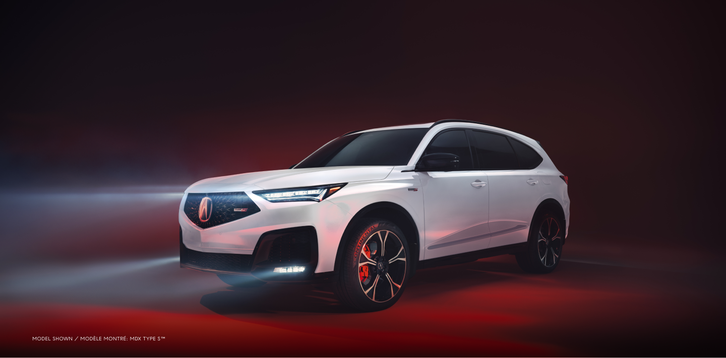 3/4 side front view of white MDX, with its headlights on, in a studio lit with red light.