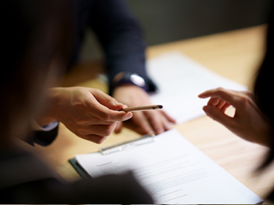 An Acura salesperson passing a pen to a customer to sign a document. // Un vendeur Acura passant un stylo à un client pour signer un document